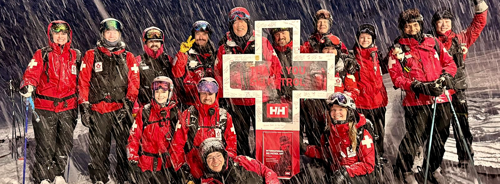 Ski patrollers pose in front of Helly Hansen cross at Marmot Basin, Jasper AB, for International Ski Patroller Day 2026